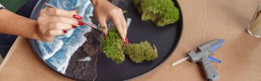 Woman decorator making green ikebana on tray with epoxy resin in florist studio. High quality photo