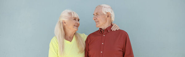 Happy positive senior woman and loving man hug standing on light grey background in studio. Love and family relationship