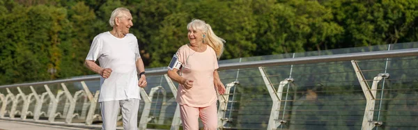Glückliche Senioren Mit Handy Und Kopfhörer Laufen Einem Sommertag Gemeinsam — Stockfoto