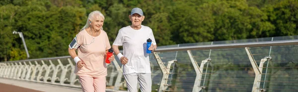 一对老夫妇 带着一瓶水 在城市人行天桥上一起跑步训练 积极的生活方式和保健 — 图库照片