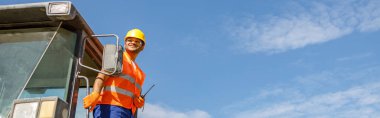 Beton fabrikasının inşaat sahasında yük kamyonu platformunda dururken telsizi elinde tutan mutlu işçi.