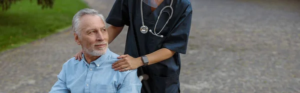 Återställa Manliga Patienten Rullstol Tittar Bort Promenad Med Sjuksköterska Utomhus — Stockfoto