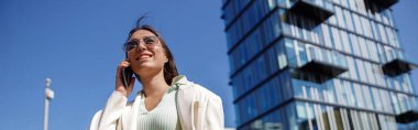 Attractive young woman in white suit near business centre. City walking concept