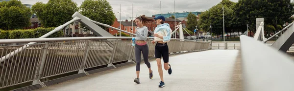 Дві Жінки Спортивному Одязі Бігають Мосту Слухають Музику Проведення Тренінгів — стокове фото