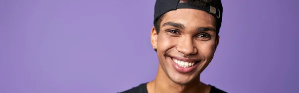 Portrét Usměvavého Latinskoamerického Transsexuála Černém Tričku Čepici Purpurovém Pozadí Šťastný — Stock fotografie