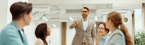 Smiling man in glasses presenting a new project to co-working colleagues