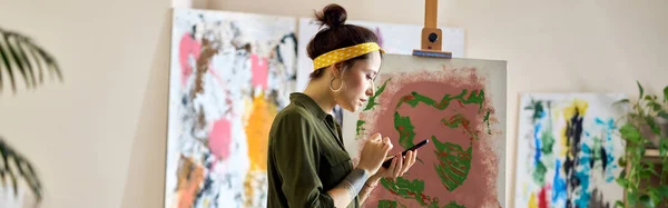 Vista Lateral Jovem Mulher Usando Seu Smartphone Enquanto Cria Pintura — Fotografia de Stock