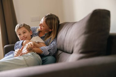 Anne ve oğlu evlerinde kanepede gıdıklanıyor. Mutlu annelik ve çocukluk