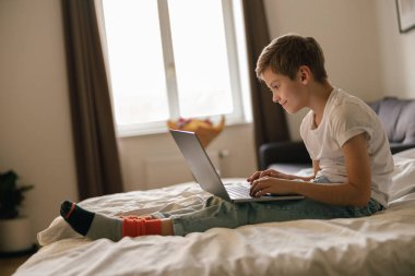 Evde, yatak odasında dizüstü bilgisayarlı küçük şirin çocuk çizgi film izliyor. Yüksek kalite fotoğraf