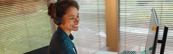 Smiling woman designer in headphones works in home office. High quality photo