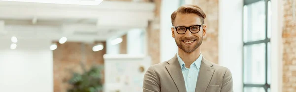 stock image Happy young male employee in glasses standing with his colleagues in the background