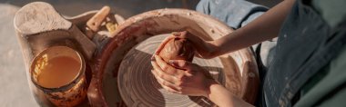 Seramik atölyesinde çömlek çarkında kil çanak çömlek yapan yetenekli genç kadının yüksek açılı görüntüsü