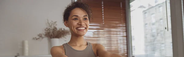 stock image Afro american woman doing exercises for hands by online tutorials on laptop at home