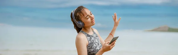 Young Woman Sportswear Listening Music Headphones Beach Background Ocean — Stok fotoğraf