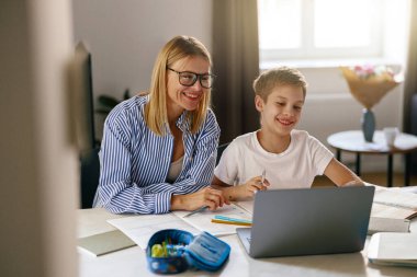 Anne, küçük oğluna dizüstü bilgisayar ödevinde yardım ediyor. Yüksek kalite fotoğraf