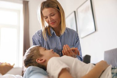 Gülümseyen anne ve küçük oğlu evde yatakta yatıyor. Annelik. Yüksek kalite fotoğraf