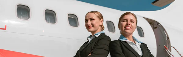 Cheerful Flight Attendants Standing Back Back Airport Blurred Background — Stok fotoğraf