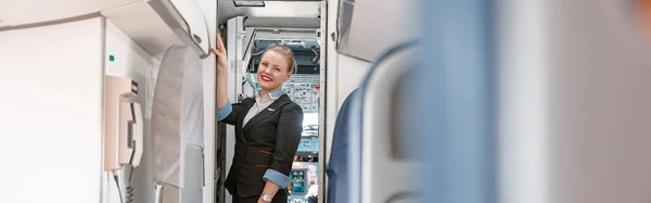 Radosna Stewardessa Mundurze Stewardessy Patrzy Kamerę Uśmiecha Się Stojąc Drzwiach — Zdjęcie stockowe