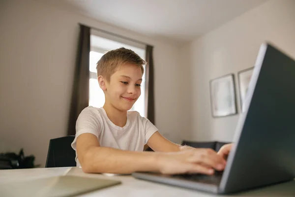 stock image Happy boy having online video lesson at laptop sitting at the table in his room. High quality photo