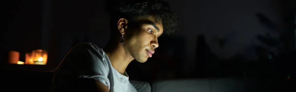 초점이 맞춰진 남자가 전자책을 읽거나 태블릿 사용하여 비디오를 어두운 의사소통 — 스톡 사진