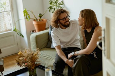 Oturma odasında sevgi ve şefkatle kucaklaşan ve gülümseyen bir çift. İyi ilişkiler zamanı.