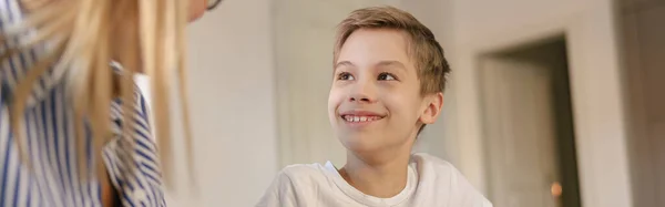 彼のお母さんの助けを借りて学校の宿題をするためにラップトップを使用して小さな笑顔の学校の少年 — ストック写真