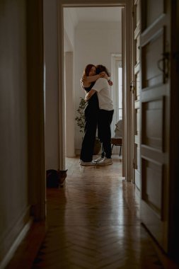 Kadın ve erkek, oturma odasında sevgi ve şefkatle sarılıyorlar. İyi ilişkiler zamanı.