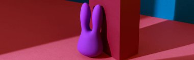 Violet dildo vibrator for clitoris with pink gift box on colored background. High quality photo