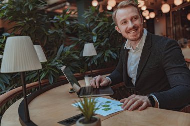 Belgelerle çalışan ve ofiste otururken dizüstü bilgisayar kullanan bir iş adamı. Yüksek kalite fotoğraf