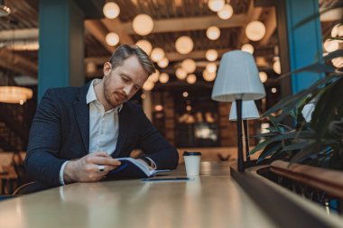 Modern çalışma saatlerinde not defterine bakan bir iş adamı. Yüksek kalite fotoğraf