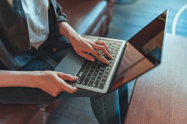 Kanepede rahat bir şekilde otururken dizüstü bilgisayarda çalışan kadına yakın çekim. Yüksek kalite fotoğraf