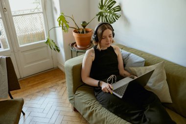 İnternette öğrenmek için dizüstü bilgisayar kullanan ya da evde kanepede yatarken film izleyen bir kadın.