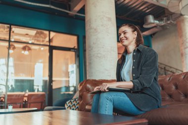 Serbest çalışan kadın çalışma alanında dinleniyor ve yan tarafa bakıyor. 