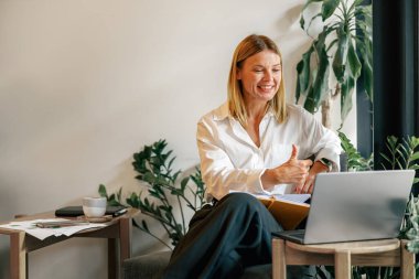 Kadın, kafede otururken müşteriyle görüntülü konuşma yapıyor. Mesafe çalışma kavramı