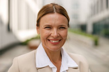 Modern binanın arka planında duran ve kameraya bakan kadın girişimci