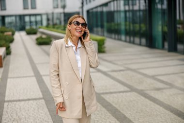 Gülümseyen kadın ofis çalışanı modern bina geçmişi hakkında konuşuyor. 