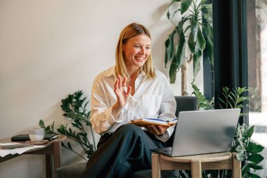 Kadın, kafede otururken müşteriyle görüntülü konuşma yapıyor. Mesafe çalışma kavramı