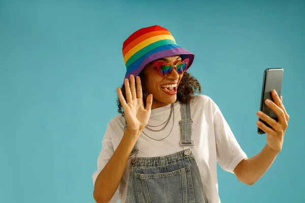 Smiling Woman Rainbow Cap Talking Video Call Waving Blue Studio — Stok Foto