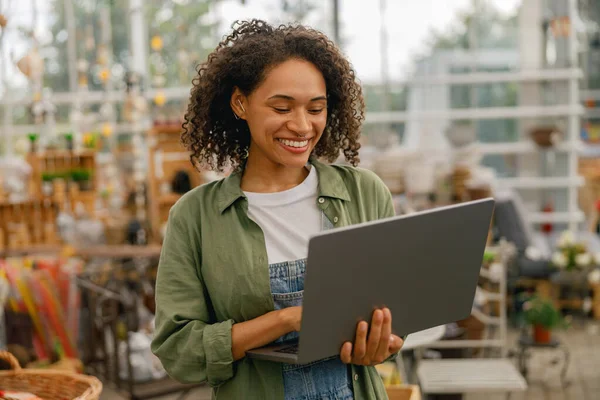 stock image Female gardening shop owner working on laptop on garden store background. High quality photo