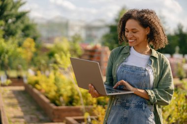 Kadın bahçıvan, bitki merkezinin arka planında otururken dizüstü bilgisayarda çalışıyor. Yüksek kalite fotoğraf