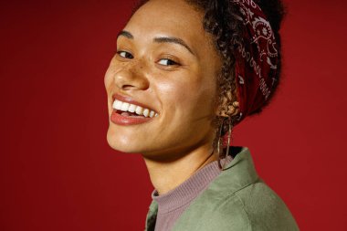 Çekici bir kadının portresi kırmızı stüdyo arka planında duran bir gülümsemeyle kameraya benziyor. 