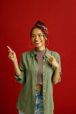 Heyecanlı genç bir kadının portresi kırmızı stüdyo arka planında harika bir fikirle yan yana duruyor.