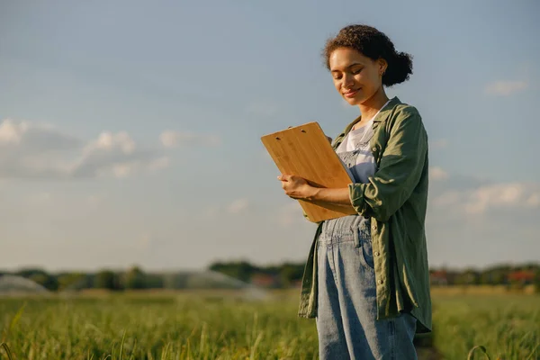 stock image Female agronomist with clipboard standing field during harvesting. Agricultural occupation concept