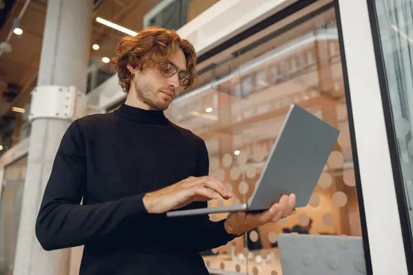 Fokusert Frilanser Som Jobber Med Laptop Mens Står Moderne Kollegabakgrunn – stockfoto