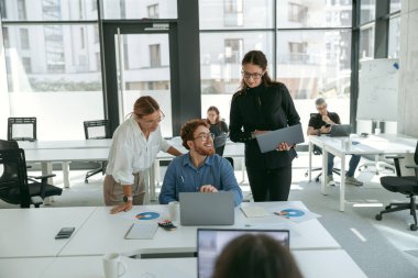 Bir grup genç iş adamı ofis masasında otururken bir şeyler tartışıyor ve gülümsüyor.