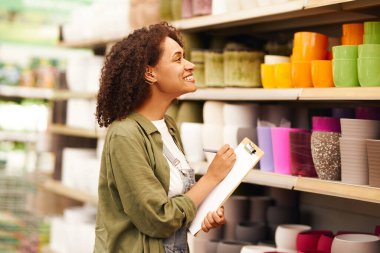 Gülümseyen kadın bahçıvan bahçe merkezinde dururken not alıyor. Yüksek kalite fotoğraf