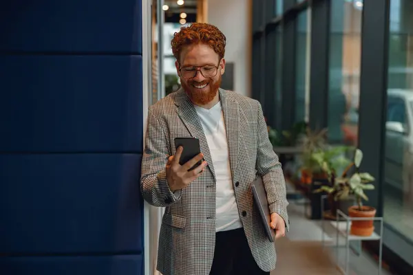 現代のオフィスの背景にラップトップが立ってスマイルビジネスマンと電話を使用 — ストック写真