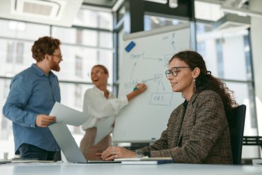 İş kadını, ofisteki meslektaşlarıyla sunum yapıyor ve iş stratejisini tartışıyor.