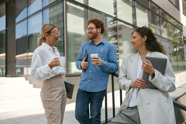 Cheerfull business people talking and laughing during break time outside of office
