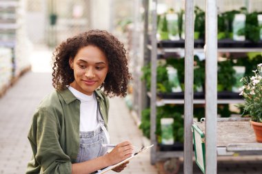 Gülümseyen kadın bahçıvan bahçe merkezinde dururken not alıyor. Yüksek kalite fotoğraf